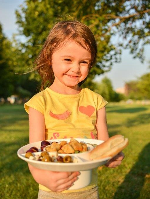 Young girl holding a white bowl plate product filled with food for kids