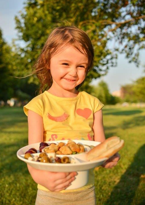 Young girl holding a white bowl plate product filled with food for kids
